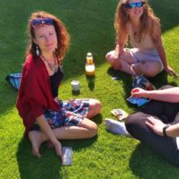drei Personen sitzen auf einer Wiese in der Sonne und rauchen