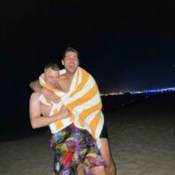 zwei Personen in Badehosen in der Nacht am Strand