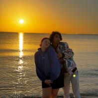 zwei talk2move Mitarbeiter am Strand im Hintergrund ein Sonnenuntergang