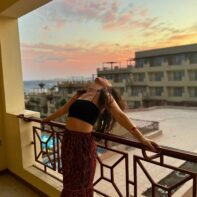 eine junge Frau lent sich über das Balkongeländer eine Hotels in Ägypten